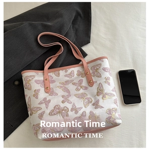 Detailed embroidery of pink butterflies on a white fabric tote bag with leather straps