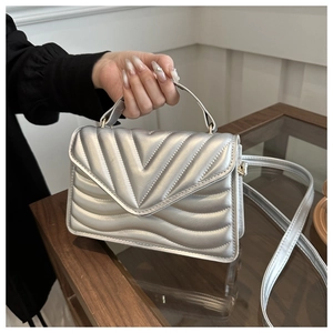 Detailed close-up of a silver quilted handbag with V-flap design and metallic chain strap
