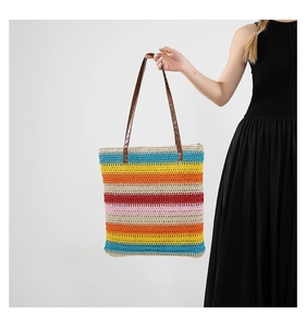 Detail of colorful striped woven tote bag with brown leather straps on black dress