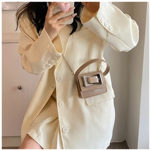 Detail of silver metal buckle and rigid rectangular design on beige crossbody bag
