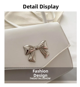 Close-up of elegant silver bow detail and fine stitching on a white leather handbag