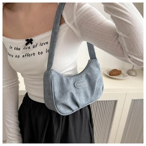 Close-up detail of light blue denim textured hobo bag with Fashion & Bag metal plaque