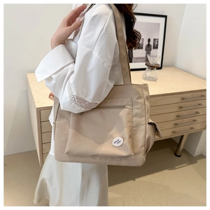Close-up of beige canvas tote bag with side pocket and Good Luck patch for students