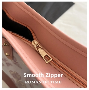 Close-up of smooth light gold metal zipper on pink butterfly print leather tote bag