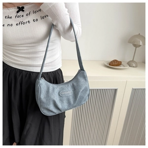 Detailed view of light blue ruched fabric hobo bag worn on shoulder in a cozy interior