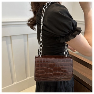 Detail of brown crocodile pattern shoulder bag with a stylish silver chunky chain strap