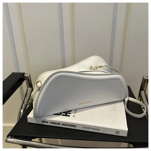 Detail of white leather shoulder bag with gold lettering on New Urban Housing book