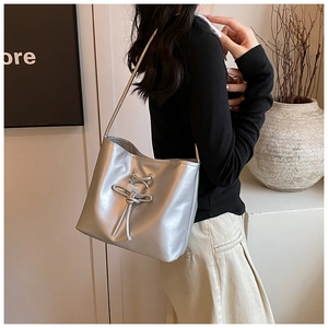 Detail of silver metallic PU shoulder bag featuring decorative lace-up knots and ties