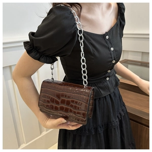 Close-up of vintage brown crocodile texture crossbody bag with silver chain strap