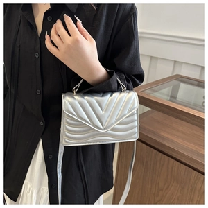Detail shot of silver quilted faux leather crossbody bag with V-shaped stitching pattern