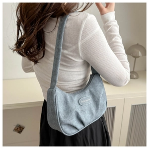 Detail of light blue pleated underarm bag showing fashion brand tag and strap texture