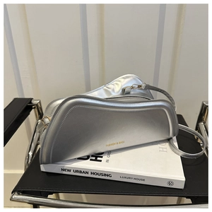 Detailed shot of metallic silver irregular curved shoulder bag with adjustable strap
