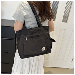 Detail view of large black nylon tote bag with side pockets and good luck embroidery