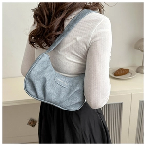 Detail of light blue pleated croissant bag with fashion tag and wide shoulder strap