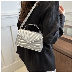 Close-up of a silver quilted crossbody bag with V-shaped stitching and chain strap
