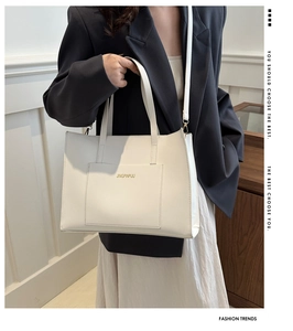 Large white tote bag worn by a model, showing spacious size and elegant shoulder strap design