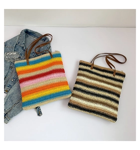Detail of woven straw tote bags with colorful horizontal stripes and brown leather handles