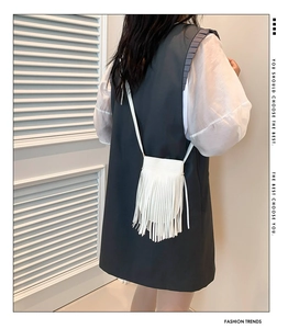 Detailed view of white fringed crossbody bag with long tassels and matching strap