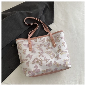 Close-up of intricate butterfly embroidery on canvas tote bag with pink leather trim