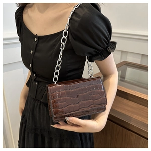 Detail of dark brown faux crocodile leather shoulder bag with a chunky silver chain strap