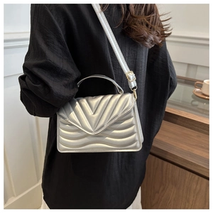 Detail of silver quilted crossbody bag with metallic finish and gold metal clasp
