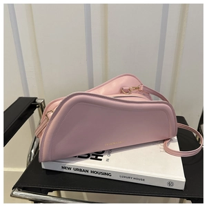 Close-up of pink geometric shoulder bag with gold hardware and embossed fashion text