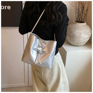 Close-up of silver ballet-style bucket bag featuring pearl texture and lace-up details