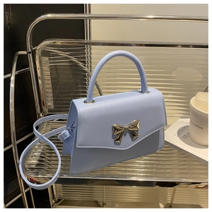 Detail view of sky blue bow handbag with silver hardware on industrial metal shelf
