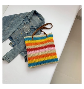 Detail view of colorful striped woven tote bag with premium brown leather handles