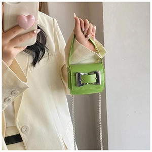 Detail of green mini handbag with large silver bow buckle and chain shoulder strap
