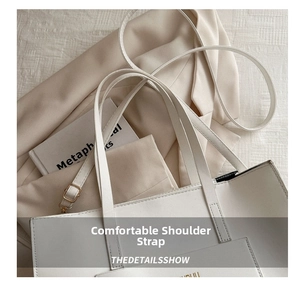 Detail of white leather tote bag with slim shoulder straps and gold buckle accents