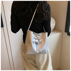 Chic silver bow shoulder bag shown on model in a minimalist modern studio setting