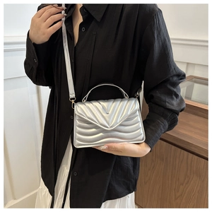 Detail of silver V-quilted small square bag with metallic finish and metal chain strap