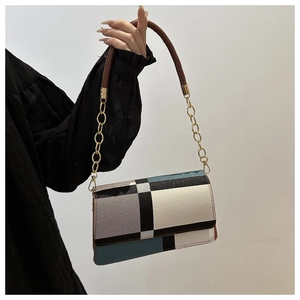 Detail of color-block leather handbag with geometric patterns and golden chain strap