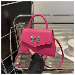 Detail of rose pink handbag featuring a silver bow metal buckle and curved top handle