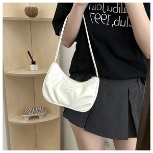 Detailed close-up of white pleated crescent shoulder bag with embossed fashion label