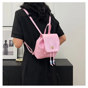 Rear view of a pink mini backpack with beaded drawstring and gold twist lock on black dress