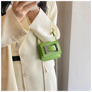 Mini avocado green leather bag featuring a chunky silver buckle and chain strap on a model