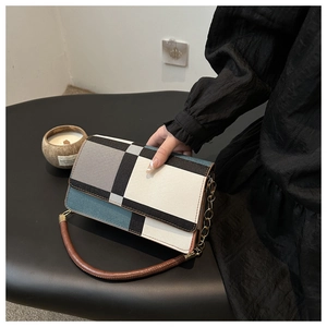 Detail of color-block flap handbag featuring geometric patterns and gold chain strap