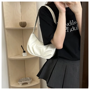 Detail of white pleated crescent underarm bag showing faux leather texture and logo