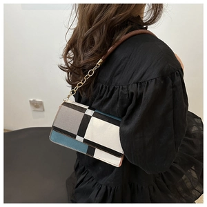 Detail of a color-block shoulder bag with gold chain link and brown leather strap