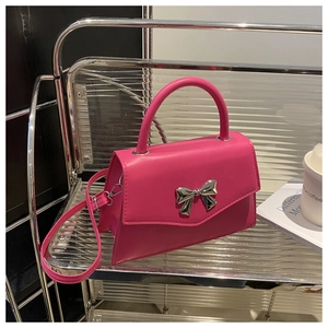 Detail of fuchsia trapezoid bag with silver metal bow and smooth synthetic leather