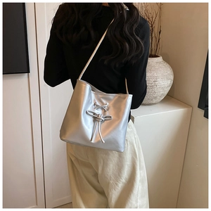 Minimalist silver metallic tote bag with decorative knot shown in a daily lifestyle setting