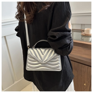 Close-up of silver V-quilted crossbody bag with metallic finish and chain strap details