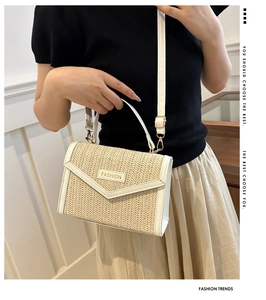 Detail of woven straw crossbody bag with white leather trim and metal fashion logo