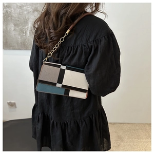 Detail of color-block baguette bag with geometric leather panels and gold chain strap