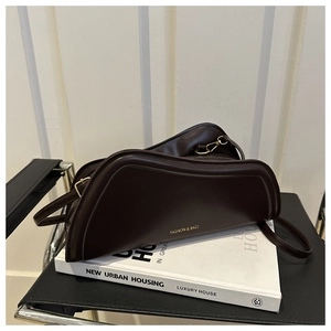 Detail of dark coffee PU leather underarm bag with gold logo on a vintage black chair