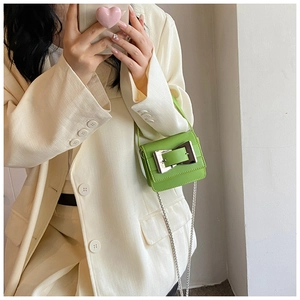 Detail view of mini green leather crossbody bag with bold silver buckle and chain strap