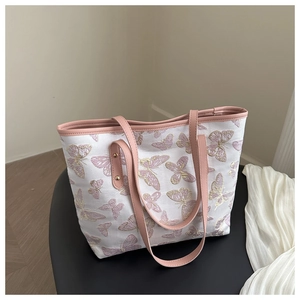 Detail of pink butterfly embroidery on a white canvas tote bag with leather handles