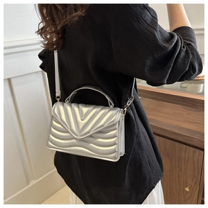 Detail of silver crossbody bag with metallic V-shaped quilting and gold hardware